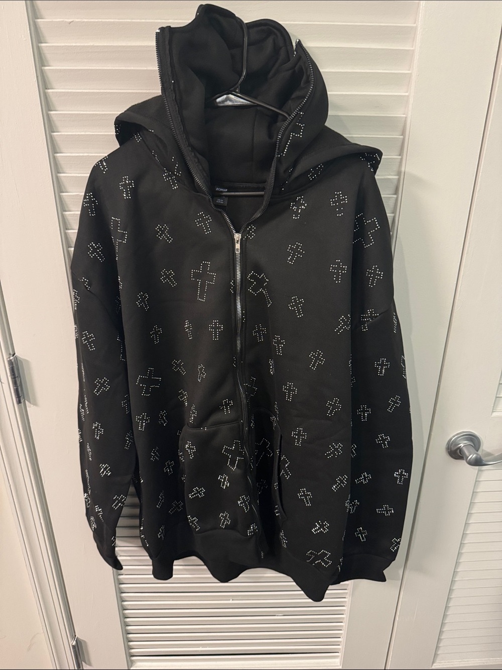 “ROMWE” hoodie features crystals cross embellishments and a full zipper front.